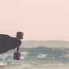 A woman holding a longboard while standing near a scenic beach