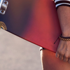 Person holding a red longboard with silver trucks and wheels.