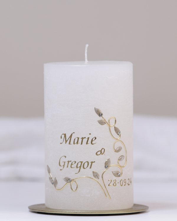 Elfenbeinfarbene Hochzeitskerze mit geschwungener goldener Blumenranke, Eheringen und funkelnden Strassteinchen.