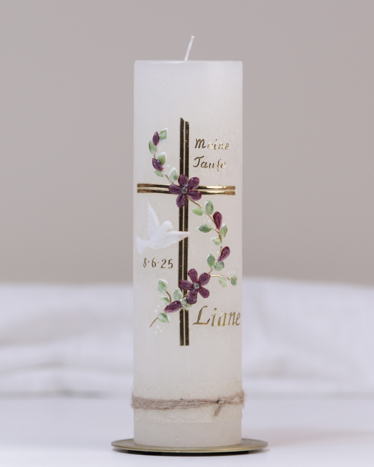 Elfenbeinfarbene Taufkerze mit grün-goldener Verzierung aus Kreuz, Blumenranke, Taube und „Meine Taufe“-Schriftzug.