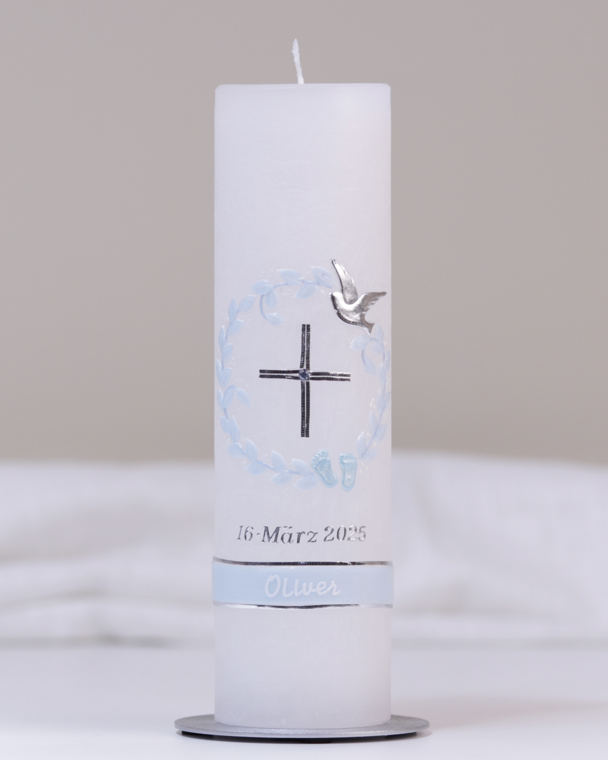 Weiße Taufkerze mit silber-blauer Verzierung aus Kreuz, Taube, Füßchen und Kranz.
